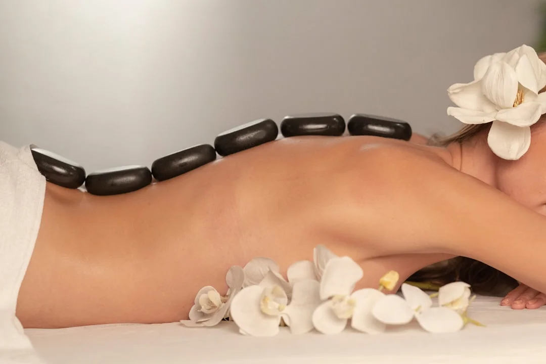 A licensed massage therapist adjusting the face cradle on a professional portable massage table in a clean, well-lit treatment room